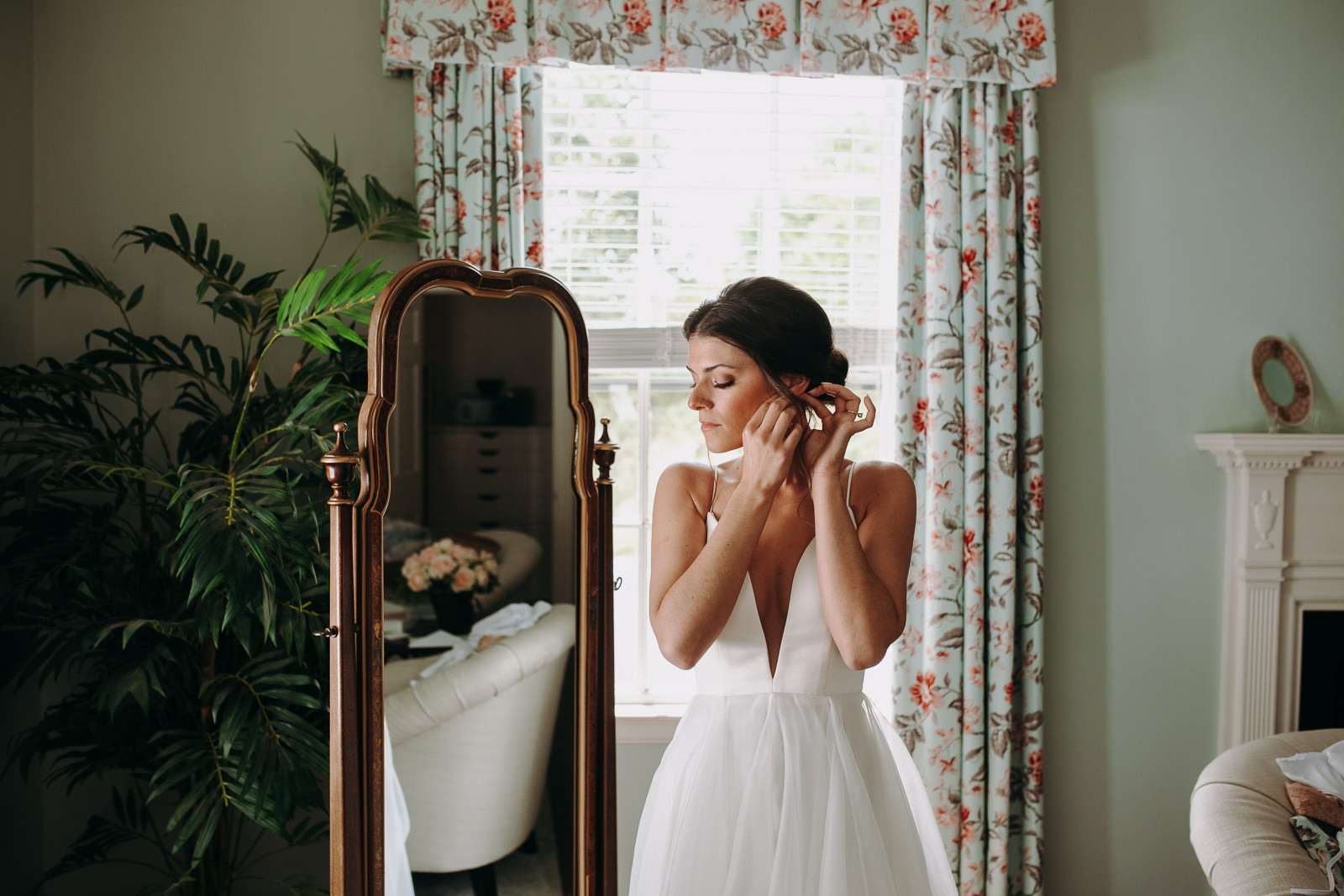 bride puts on earrings in brittland manor suite