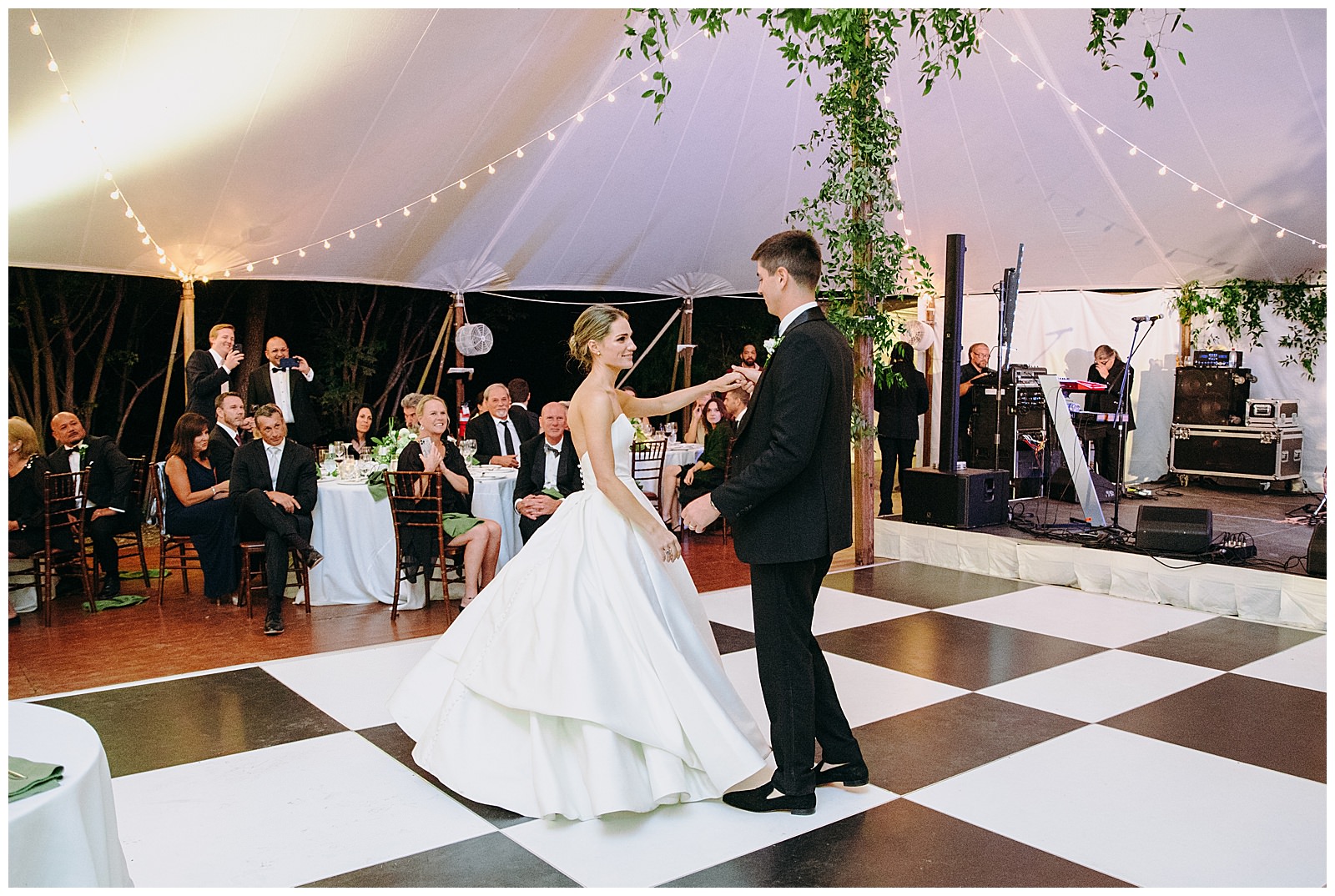 bride and groom share their first dance on a black and white dance floor at a tented reception at their Clifton Inn wedding