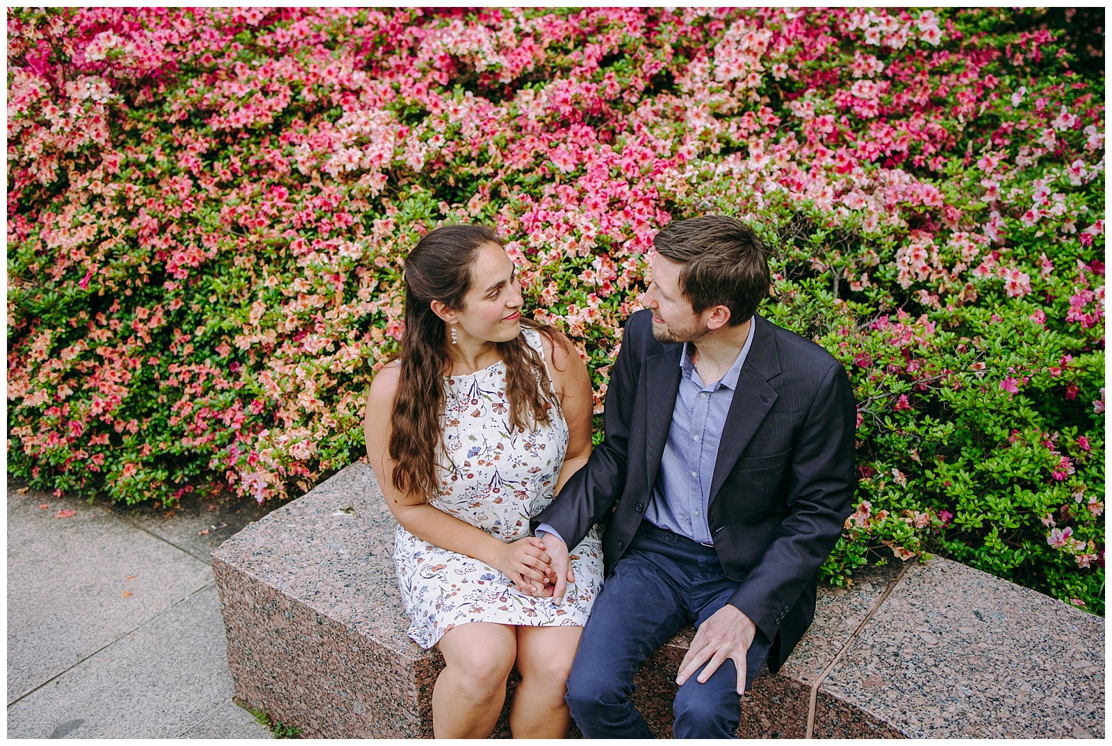 couple sitting in front of pink flowers
