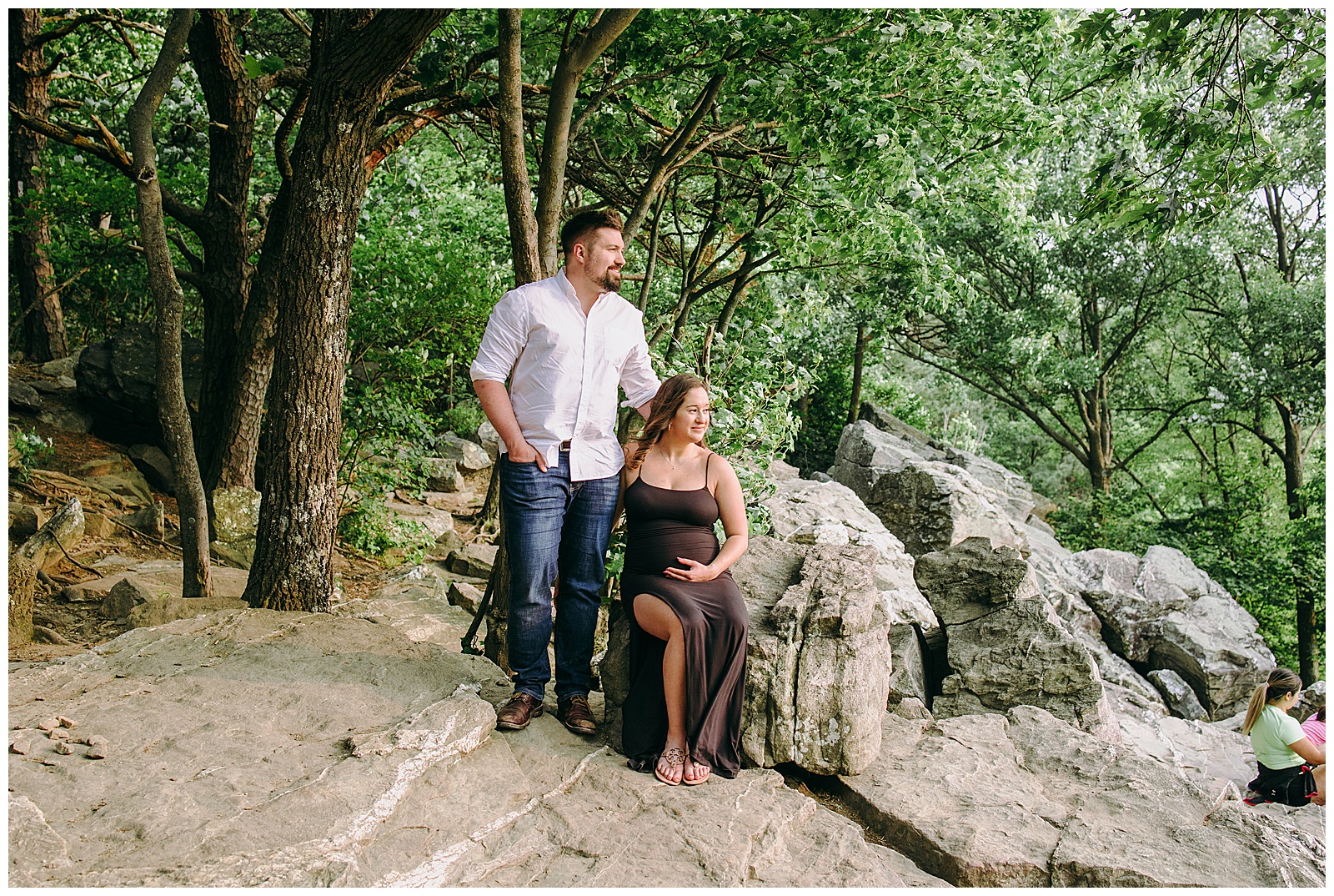 couple at their maternity session looking off to the right, man is wearing jeans and white shirt, woman is wearing black maxi dress